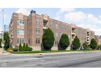 Brick apartment building featuring balconies, lush greenery, and well-maintained landscaping at 450 E Ohio St # Apt 118, Indianapolis, IN 46204