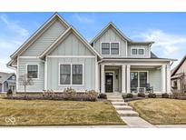 Charming two-story home with light blue siding, black trim, and a welcoming front porch with rocking chairs at 4722 Wellswood, Carmel, IN 46033