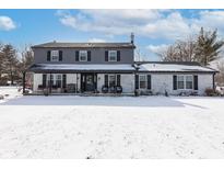 Charming two-story home featuring a covered front porch and snow-covered front yard at 7089 W 150 N, Greenfield, IN 46140