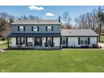Charming two-story home featuring a front porch, gray siding, a white brick facade, and a lush green lawn at 7089 W 150 N, Greenfield, IN 46140