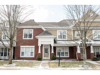 Charming townhome featuring a brick facade, complemented by tan siding and mature trees at 15542 Crofton Pl, Westfield, IN 46074