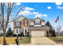 Charming two-story brick home featuring an attached garage, manicured lawn and an American flag at 18751 Whitcomb Pl, Noblesville, IN 46062