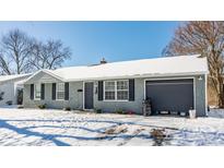 Charming single-story home with a gray brick exterior, complemented by snow covered landscaping and an attached garage at 3516 Wellington Ave, Indianapolis, IN 46226