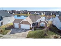 Charming brick home with a three-car garage, a well-manicured lawn, and a tranquil pond view at 8651 Blue Marlin Dr, Indianapolis, IN 46239