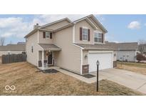Charming two-story home features tan siding, red shutters, covered porch, and an attached two-car garage at 15457 Old Pond Cir, Noblesville, IN 46060