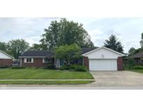 Charming brick ranch home features a two-car garage and a lush green lawn at 1701 Beech N Dr, Plainfield, IN 46168