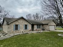 Charming single story tan brick home with a two car garage, blue shutters, and landscaped front yard at 2129 Heather Rd, Anderson, IN 46012
