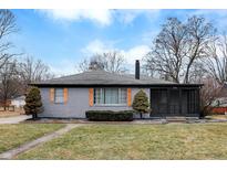 Charming single-story home features a gray brick exterior, shuttered windows, and well-maintained landscaping at 6144 N Dearborn St, Indianapolis, IN 46220