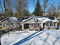 Charming gray home with stone accents, a welcoming wreath, and a snowy front yard at 717 Washington Ct, Anderson, IN 46011