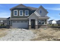 Two-story home featuring an attached garage, green siding and charming architectural details against a clear blue sky at 8931 Alexander Ridge Dr, McCordsville, IN 46055