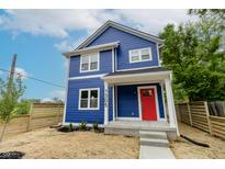 Charming blue two-story home featuring a bright red front door and manicured landscaping at 1305 W 23Rd St, Indianapolis, IN 46208
