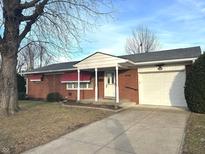 Charming brick home featuring red awnings, a white garage door, and a well-maintained front yard at 1925 N Auburn St, Indianapolis, IN 46224