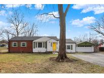 Charming single-story home featuring a yellow door, brick accents and a well-manicured front yard at 2849 Canterbury Ln, Indianapolis, IN 46220