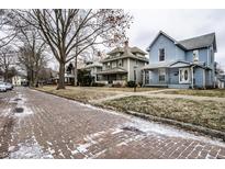 Charming street with brick road and sidewalks lined with well-maintained, unique homes and mature trees at 323 N Layman Ave, Indianapolis, IN 46219