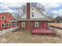 Two-story red brick home featuring a brick chimney, red door, and a small red porch at 515 S East St, Plainfield, IN 46168