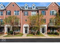 Brick townhome with black shutters, complemented by green landscaping and a blue sky backdrop at 53 Monon Ln, Carmel, IN 46032
