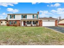 Inviting two-story home featuring a brick chimney, attached two-car garage, and manicured lawn at 5549 Hollister Dr, Indianapolis, IN 46224