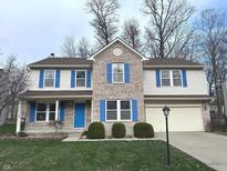 Charming two-story home with a brick facade, blue shutters, a well-manicured lawn, and attached two car garage at 7234 Tresa Dr, Indianapolis, IN 46239