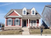 Charming two-story red home with inviting front porch and manicured lawn on a sunny day at 12964 Walbeck Dr, Fishers, IN 46037