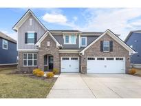 Charming two-story home featuring brick accents, a two-car garage, and manicured landscaping at 15949 Black Willow Ln, Fishers, IN 46040