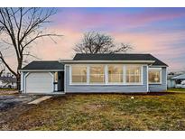 Charming single-story home with a light blue exterior, attached garage, and large picture window at 1818 Arlene Dr, Indianapolis, IN 46219