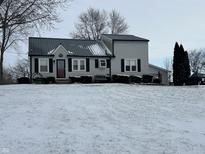 Charming two-story home features a metal roof, black shutters, covered porch, and winter landscaping at 1905 Apple St, Greenfield, IN 46140