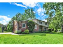 Two-story brick home featuring mature trees, a well-manicured lawn, and beautiful landscaping at 502 Ironwood Dr, Carmel, IN 46033
