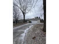 A single-Gathering home with a two-car garage and a long driveway on an overcast day at 6533 Parker Ln, Indianapolis, IN 46220
