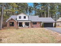 Charming brick home with a white gabled roof and well-maintained landscaping surrounded by mature trees at 7643 Dean Rd, Indianapolis, IN 46240