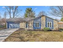 Charming stone and siding home with well-manicured lawn and an attached garage at 8305 Warbler Way, Indianapolis, IN 46256
