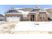 Charming brick home featuring a two-car garage, gabled roof, and inviting front entrance during winter at 9716 Holborn Ave, McCordsville, IN 46055
