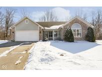 Charming front exterior showing a two-car garage and brick accents, partially covered in snow at 9959 Comb Run Ct, Avon, IN 46123