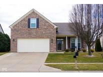 Charming brick home featuring a two-car garage, manicured lawn, and inviting covered porch with seating at 1219 Kingfisher Dr, Greenwood, IN 46143