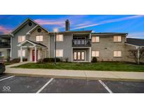 A beautiful exterior view of a two-story apartment home with grey siding and manicured lawn at 12588 Tennyson Ln # 103, Carmel, IN 46032