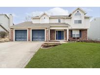 Two-story home featuring a three-car garage, brick accents, tidy lawn, and a welcoming blue front door at 1474 Derbyshire Dr, Greenwood, IN 46143