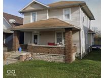 Two-story home with a covered front porch, brick pillars, and neutral siding at 304 N Hackley St, Muncie, IN 47305