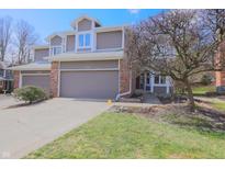 Inviting townhome with a well-maintained lawn, garage and an eye-catching bare tree on a sunny day at 8150 Foxchase Cir, Indianapolis, IN 46256