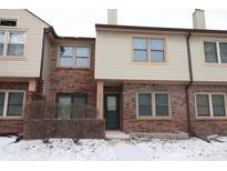 Charming townhouse featuring brick and neutral siding, complemented by snow-covered landscaping at 9523 Maple Way, Indianapolis, IN 46268