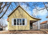Charming yellow home with a covered porch and a well-maintained yard under a partially cloudy sky at 140 Herriott St, Franklin, IN 46131