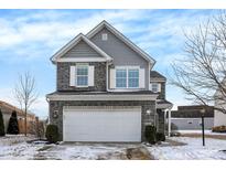 Charming two-story home featuring a stone and gray facade, a two-car garage and manicured landscaping at 19462 Chip Shot Rd, Noblesville, IN 46062