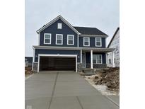 Two-story home featuring a two-car garage, a charming front porch, and blue horizontal siding at 517 Kentucky St, Fortville, IN 46040