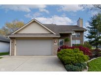 Charming brick home with a two-car garage, blue door, and beautifully landscaped front yard under a bright blue sky at 6006 Regency Dr, Columbus, IN 47203