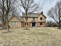 Traditional two-story home featuring a brick and wood facade with a well-maintained front lawn and mature trees at 6730 La Tour Cir, Indianapolis, IN 46278