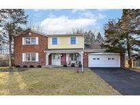 Charming two-story home featuring a brick facade, yellow siding, and a well-maintained front yard at 6838 Johnson Rd, Indianapolis, IN 46220