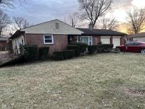 Quaint brick home featuring an attached two car garage and mature landscaping at 6921 Clemdale Ave, Lawrence, IN 46226