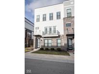 A modern three-story townhome with white siding, a grey brick base, and a small black railing balcony at 9748 Junction Station, Fishers, IN 46037