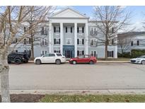 Three-story building showcasing classic architectural details, complemented by a row of parked cars at 12863 Tradd St # 1D, Carmel, IN 46032