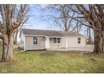 Charming single-story home featuring light beige siding and a well-maintained lawn surrounded by mature trees at 411 Jewell St, Columbus, IN 47203