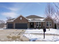 Charming brick home with a two-car garage and snow-covered yard and driveway in a suburban neighborhood at 5397 John Quincy Adams Ct, Plainfield, IN 46168