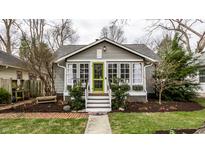 Charming gray craftsman home featuring a green door, gabled roof, and beautifully landscaped front yard at 5626 Winthrop Ave, Indianapolis, IN 46220